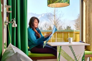 Wenn Du Urlaub im Explorer Hotel Garmisch machst, hast Dun ein helles und modernes Zimmer mit tollem Ausblick und gemütliches Sitzecke im Panoramafester!