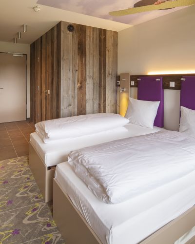 Die Hotelzimmer in den Explorer Hotels sind mit einem freundlichen lila und urigem Holz ausgestattet. Fühl Dich wohl in den modernen Explorer Design-Zimmern.